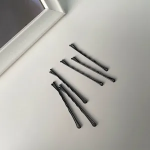 Set of minimalist black wavy metal hair pins with rounded tips on a grey background