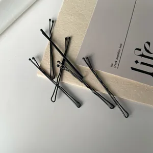Detailed macro view of black wavy metal hairpins with protective round tips on the ends