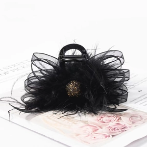 Elegant black feather hair claw with mesh bow and glitter sphere on vintage magazine