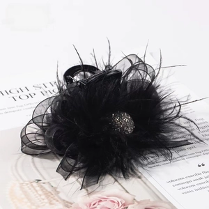 Detailed view of elegant black feather hair claw with mesh bow and sparkling rhinestone ball