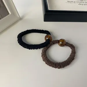 Detail of black and brown pleated scrunchies featuring decorative translucent beads