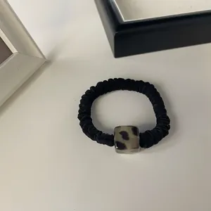 Detail of black pleated hair tie with a square leopard print resin bead ornament