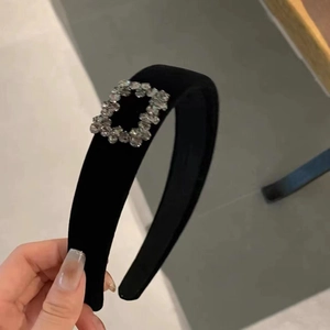 Dettaglio del cerchietto in velluto nero con una lussuosa fibbia quadrata di strass