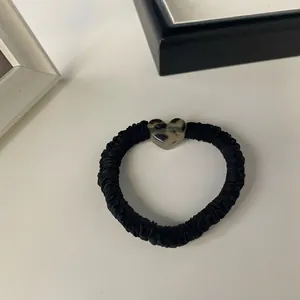 Detail of black satin scrunchie featuring a stylish leopard print heart-shaped resin charm