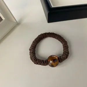 Detail of dark brown pleated scrunchie with a tortoiseshell patterned resin bead
