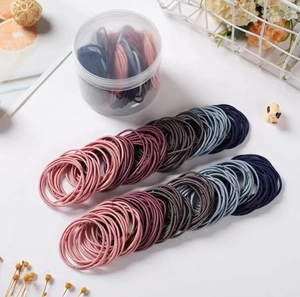 Gros plan d'élastiques à cheveux couleurs Morandi avec un tube de rangement épuré