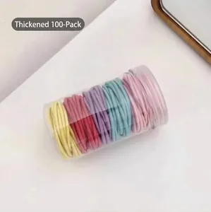 Vue détaillée de 100 élastiques à cheveux épais dans un contenant cylindrique clair