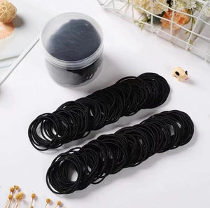 Lot d'élastiques fins noirs rangés dans un pot transparent sur un bureau blanc épuré