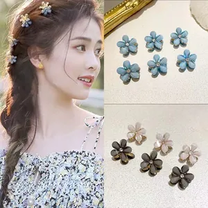 Détail de petites pinces à cheveux en forme de fleur avec cristal central en tons pastel