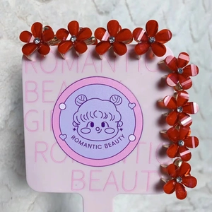 Gros plan de pinces à cheveux fleurs orange translucide avec strass sur une carte