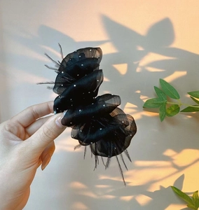 Detail view of black mesh hair claw with sparkling crystals and soft feather accents