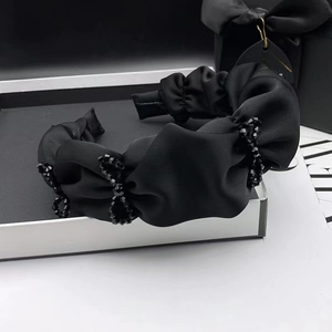 Elegant black satin pleated headband with beaded details displayed in a luxury gift box