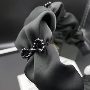 Elegant black satin pleated headband with shimmering beaded bow and vintage texture
