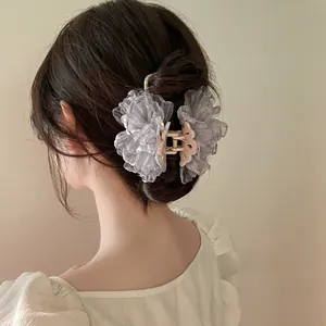 Detail of elegant smoky lavender tulle flower hair claw clip worn by a model in a cozy setting