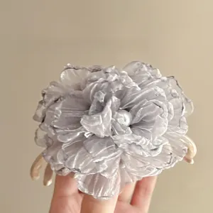 Close-up of a grey organza flower hair claw clip with a pearl center and resin base