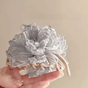 Detail of silver-grey mesh flower hair claw with champagne clip and pearl accent