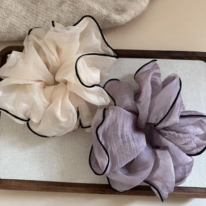 Détail de chouchous géants en organza beige et lavande avec des bords noirs ondulés