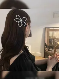 Detail of white pearl flower hair clip worn on model with elegant side-parted hairstyle