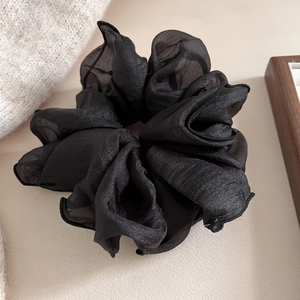 Gros plan sur un grand chouchou en organza noir avec texture de tissu plissée