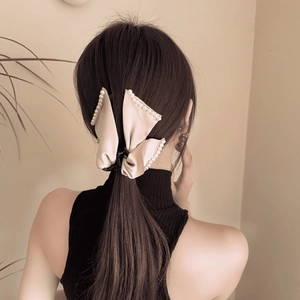 Détail d'une grande pince à cheveux avec nœud en satin crème et bordure en perles élégantes