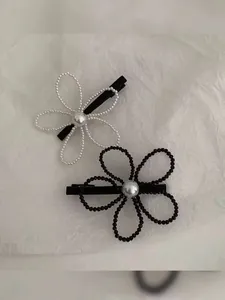 Detailed macro view of woven pearl flower hair clips in elegant black and white colors