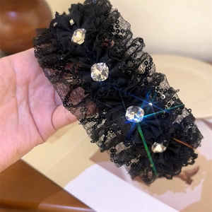 Detailed view of luxury black lace headband with shimmering sequins and large crystals
