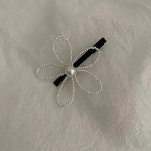 Elegant floral pearl hair clip with a minimalist five-petal design on white textured background