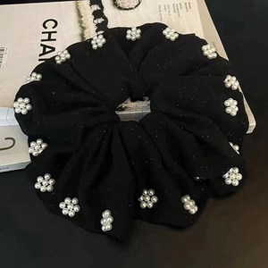 Detail of black shimmer scrunchie featuring delicate white pearl flower ornaments