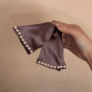Détail d'une élégante pince à cheveux en satin avec perles blanches et nœud marron