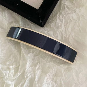 Barrette à cheveux minimaliste en acétate bleu marine et beige sur papier froissé