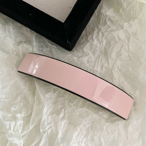 Détail d'une barrette à cheveux en acétate rose avec bords noirs de style français