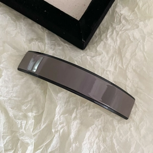 Vue détaillée d'une barrette à cheveux en acétate marron foncé avec bordure noire élégante