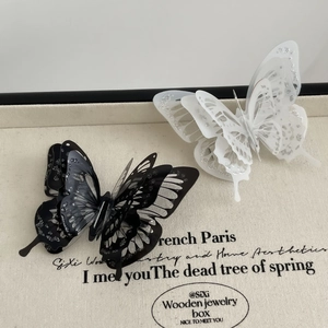Close-up of dual-layer 3D butterfly hair clips with silver glitter finish and hollow design