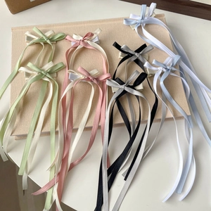 Ballet style long ribbon bow hair clips in multiple colors on a textured book surface
