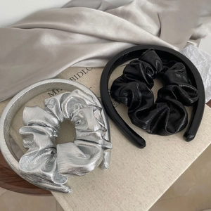 Detail of silver and black hairband sets with pleated texture on elegant fabric background