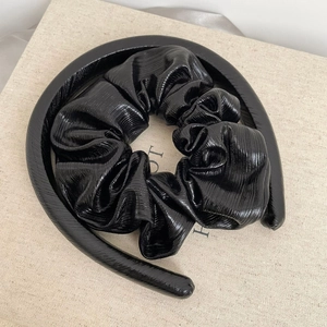Detail of black pleated faux leather headband with glossy vertical texture and thick design