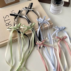 Macro detail of elegant ribbon bow hair clips in various pastel colors on a soft background