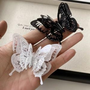 Detail of 3D layered butterfly hair clips with intricate hollow patterns and silver glitter