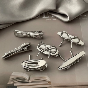 Minimalist silver metal bow hair clips set on silk fabric background for women