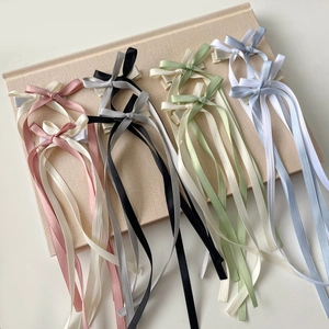 Elegant satin bow hair clips with long ribbons in six pastel colors on book base