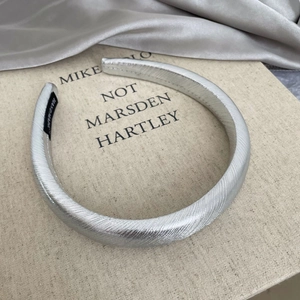 Detail view of a silver padded headband with twill texture and handmade woven label