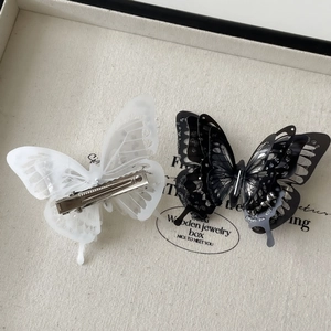Close-up showing the front and back details of black and white butterfly hair clips