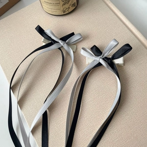 Detailed close-up of double-layered black and grey ribbon bow hair clips on textured background