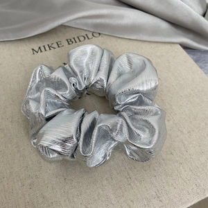Close-up of silver metallic scrunchie featuring fine vertical pleated texture and shine
