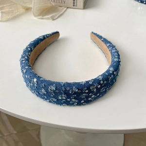 Detailed view of dark blue denim headband with silver sequins on white surface