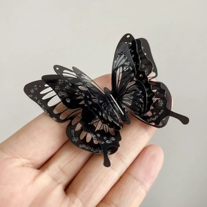Detail of 3D layered black butterfly hair clip with shimmering silver glitter accents