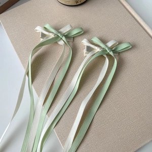 Close-up of mint green and cream double-layered satin ribbon bow clips with long streamers