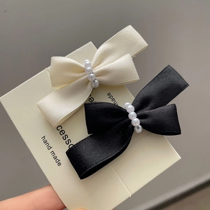 Elegant bow hair clip set with pearls in cream and black colors on display card