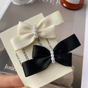 Detail of satin bow hair clips with white pearls on handmade display card