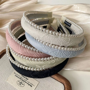 Close-up of handmade jacquard fabric headbands with pearl accents on satin background